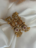 Gold earrings with gemstones on a white fabric background
