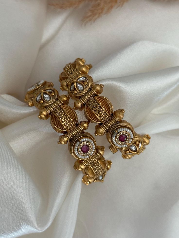 Gold earrings with gemstones on a white fabric background