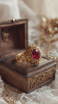 Gold ring with a red gemstone on an ornate wooden box