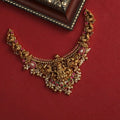 Ornate gold necklace with gemstones on a red background