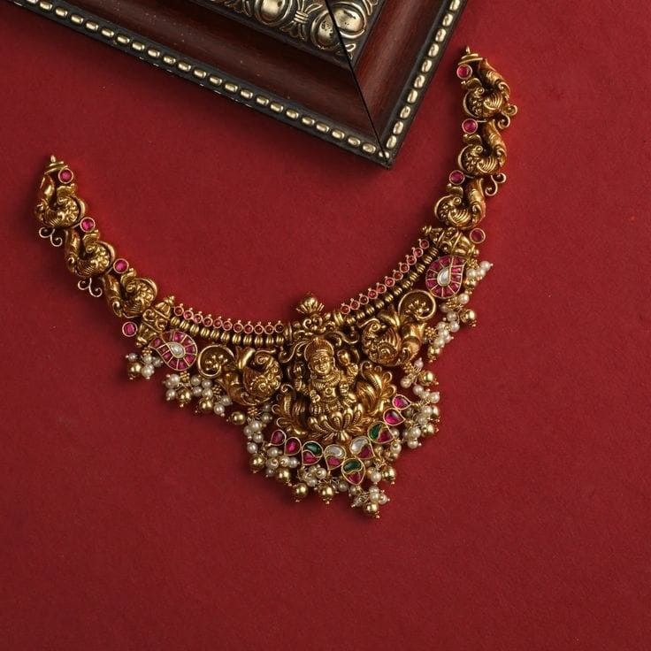 Ornate gold necklace with gemstones on a red background